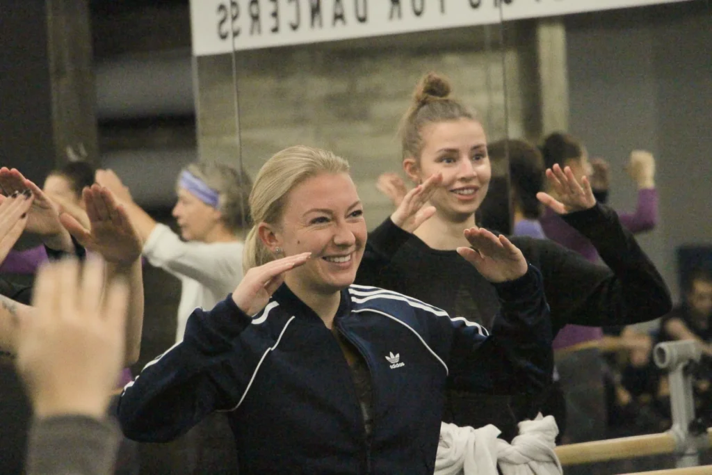 Zwei lächelnde junge Frauen, die erwartungsvoll die Arme gehoben halten