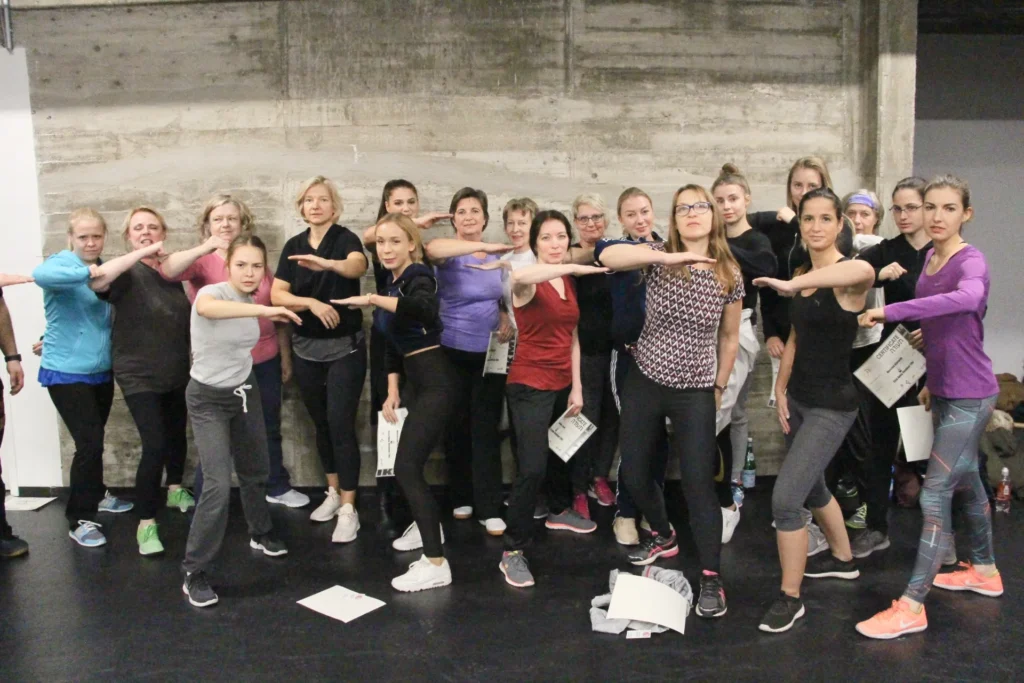 Abschlussfoto eines Seminars, eine Menge entschlossen schauende Frauen, die alle ihren Arm schützend vor sich halten